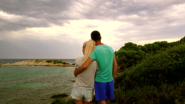 Young-couple,-embracing,-looking-at-the-stormy-sea,-Greece