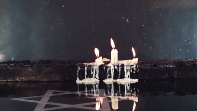 Burning-candles-on-an-old-wooden-burnt-table-and-the-Star-of-David,-rotation-360-degrees-against-a--background.