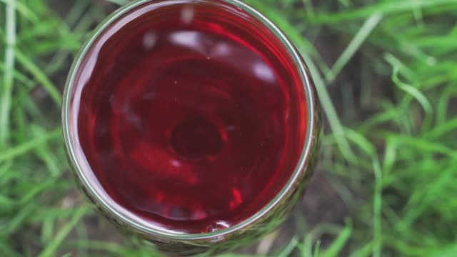 glass-of-wine-on-a-grass-background,-close-up-.
