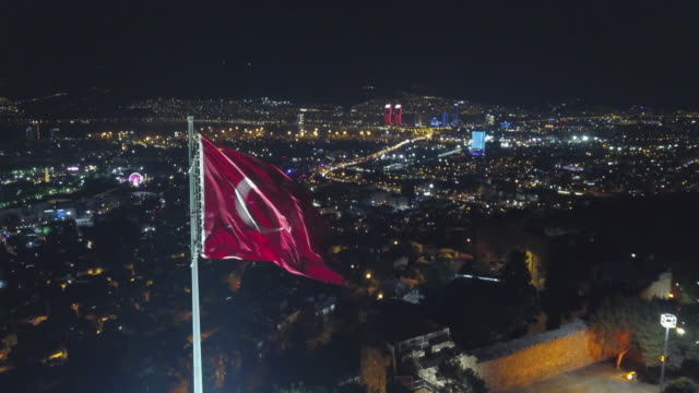 city-​​skyline-drawn-by-night-drone,--city-​​skyline-flag-in-front-of-kadifekale,-izmir