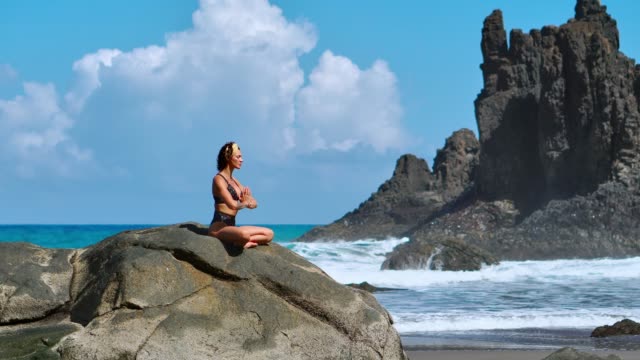 Ruhige-Meditation-Yoga.-Brünette-touristischen-Frau-meditieren-im-Lotussitz-auf-Felsvorsprung-über-dem-malerischen-Praia-da-Marinha.-Meditieren-Weibchen-auf-den-Klippen-der-Kanarischen-Inseln