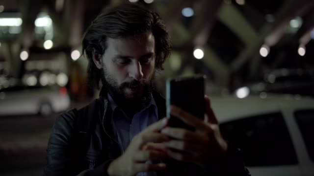 Smiling-man-making-video-call-on-smartphone-in-night-city