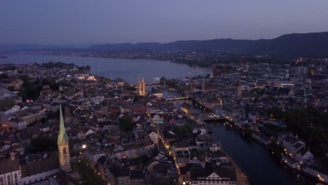 Crepúsculo-iluminado-Zurich-centro-ciudad-orilla-aérea-panorama-4k-Suiza