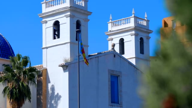Bandera-de-Valencia-cerca-de-la-iglesia-con-una-hermosa-cúpula-azul-y-campanarios-blancos