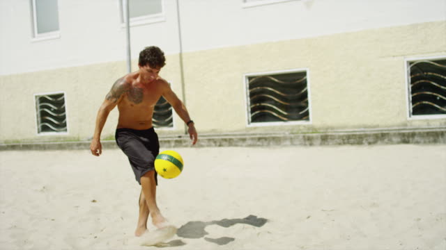 Amigos-la-práctica-las-habilidades-de-fútbol-en-la-playa-en-Brasil