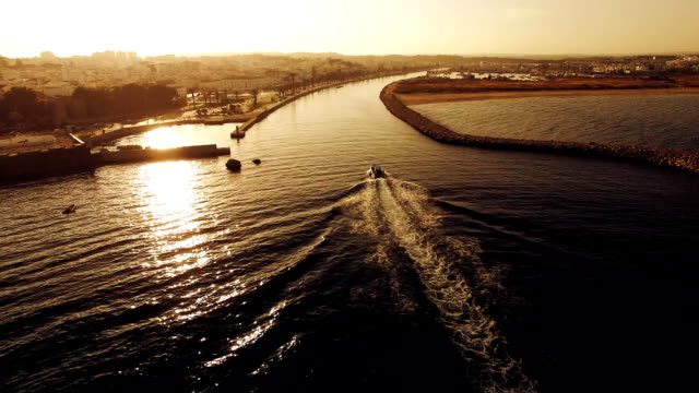 Boat-comes-into-the-harbor-at-sunset-aerial-view