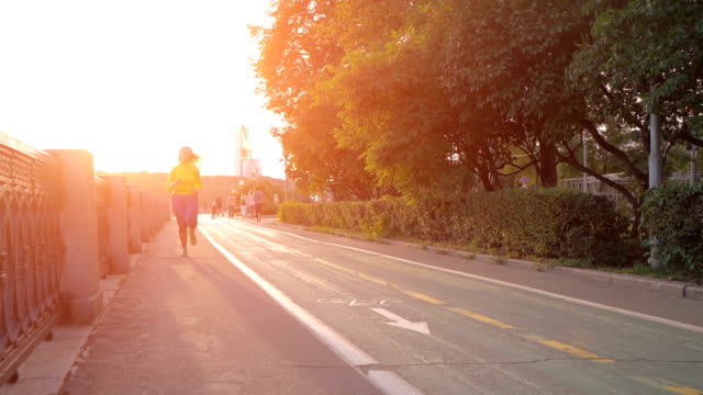 female-runner-running-at-sunset-in-city-park.