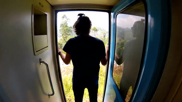 guy-in-the-shirt-rides-the-train-standing-at-the-door