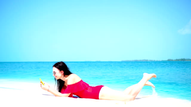 Young-beautiful-woman-lying-at-shallow-tropical-water