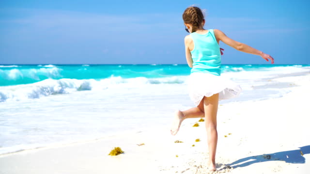 Entzückende-kleine-Mädchen-am-Strand-mit-einer-Menge-Spaß.-Sportlich-aktives-Kind-tanzen-auf-seahore