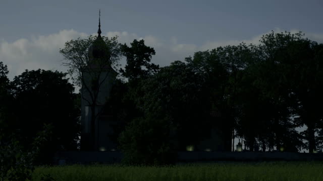 Totale-zu-kleinen-Kirche-mit-Glockenturm-und-Friedhof,-tobenden-Kerzen-auf-Gräbern.