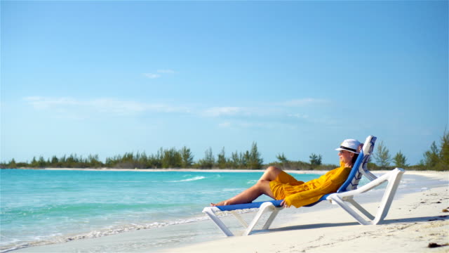 Junge-Frau-entspannen-im-Liegestuhl-an-einem-tropischen-Strand