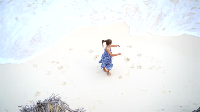 Adorable-little-girl-having-a-lot-of-fun-in-shallow-water.View-from-above-of-a-deserted-beach-with-turquoise-water