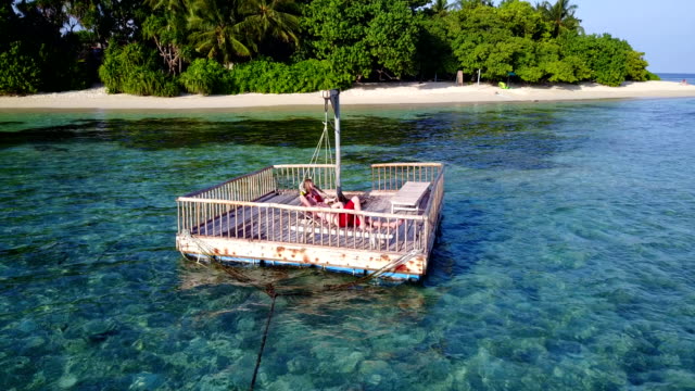v03857-fliegenden-Drohne-Luftaufnahme-der-Malediven-weißen-Sandstrand-2-Personen-junges-Paar-Mann-Frau-entspannend-auf-sonnigen-tropischen-Inselparadies-mit-Aqua-blau-Himmel-Meer-Wasser-Ozean-4k-schwimmenden-Ponton-Steg-Sonnenbaden-zusammen