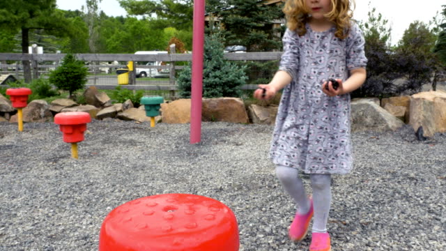Kind-spielt-mit-Kieselsteinen-in-einen-Spielplatz-im-freien