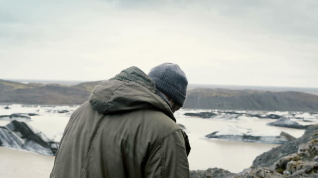 Joven-guapo-de-senderismo-en-las-montañas-cerca-de-la-laguna-de-hielo-Vatnajokull,-buscando-en-los-glaciares-en-Islandia