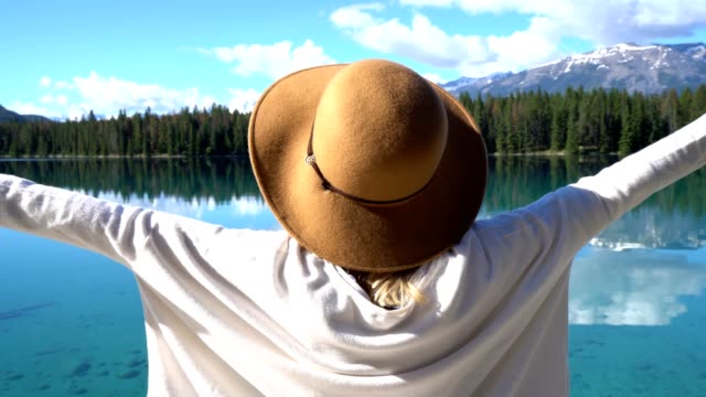 Woman-arms-outreached-by-alpine-lake-in-the-Canadians-rockies