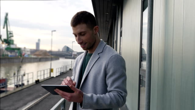 Happy-Young-Man-Using-a-Tablet-Outdoors