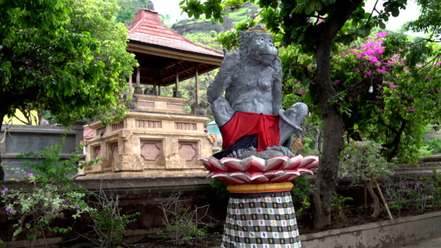 A-statue-of-a-monkey-sitting-on-a-lotus-flower.-In-the-background-jump-monkeys