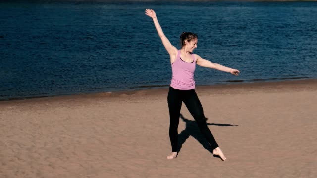 Mujer-haciendo-yoga-en-la-playa-por-el-río-en-la-ciudad.-Hermosa-vista.-Rueda-de-gimnasia