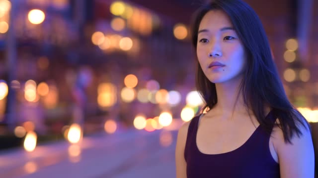 Mujer-asiática-feliz-pensando-al-aire-libre-en-la-noche
