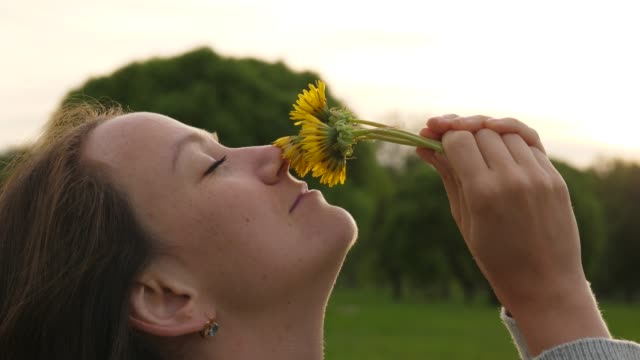 Mujer-disfruta-el-aroma-de-flores-de-diente-de-León