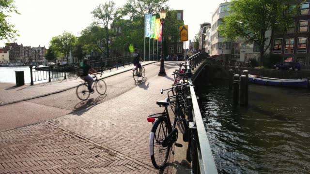 icónica-escena-holandesa,-los-ciclistas-en-el-puente-del-canal-en-Amsterdam,-Holanda-Europa