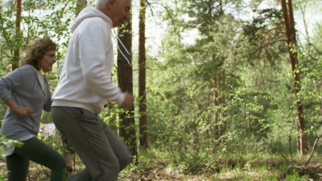 Hombre-mayor-y-mujer-para-correr-en-bosque-de-mañana