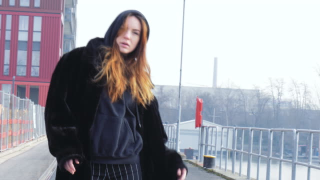 Young-Woman-Wearing-a-Large-Coat-Dancing-in-Industrial-Area