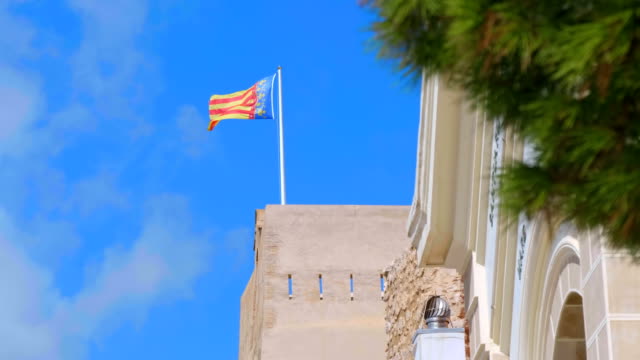 Bandera-de-Valencia-(España)-volando-sobre-el-edificio-contra-el-cielo-azul