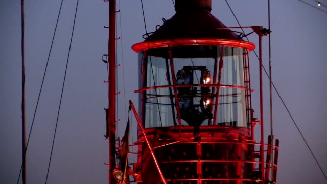Rotierende-Leuchtturm-bei-Sonnenuntergang-in-einem-Hafen
