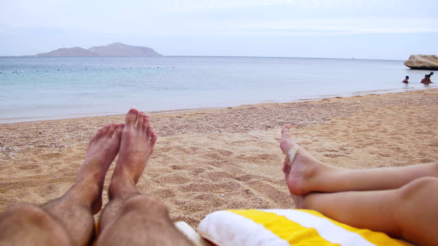 Beine-von-Menschen-am-Strand-Sonnenliege-liegen-in-der-Nähe-von-Meer