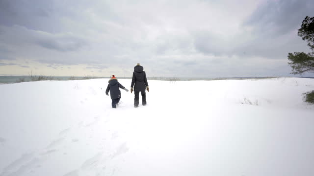 Mutter-und-Kind-zu-Fuß-am-Strand-Ontario-Kanada-im-Winter-mit-Schnee