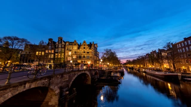 Amsterdam-city-skyline-night-timelapse-at-canal-waterfront,-Amsterdam,-Netherlands,-4K-Time-Lapse