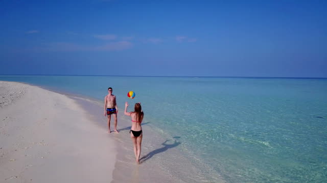 v03818-vista-aérea-de-drone-volador-de-playa-en-isla-paraíso-soleado-con-cielo-azul-aqua-mar-agua-océano-4k-2-personas-pareja-hombre-mujer-tocando-juntos-diversión-bola-blanco-Maldivas