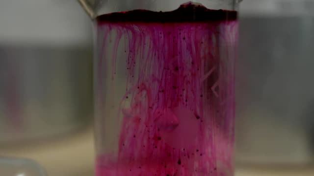 Farbige-wunderschöne-chemische-Reaktion-in-Kolben.-Rosa-oder-rote-Flüssigkeit-löst-sich-in-Kolben.-Rosa-Angelegenheit-in-den-Kolben.-Rosa-oder-rote-Flüssigkeit-löst-sich-in-Flasche