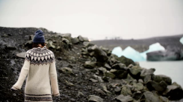 Junge-Reisende-Frau-zu-Fuß-über-die-Felsen-in-Jokulsalon-Eis-Lagune-in-Island-allein,-Erkundung-des-Anblicks