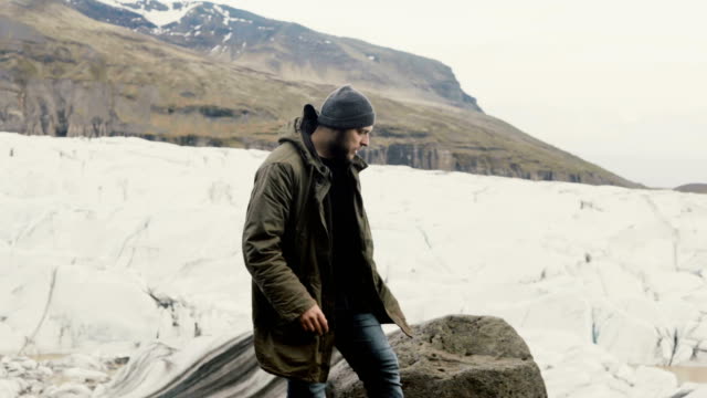 Hombre-guapo-joven-caminando-en-la-orilla-solo.-Turismo-explorando-la-laguna-de-hielo-Vatnajokull-en-Islandia