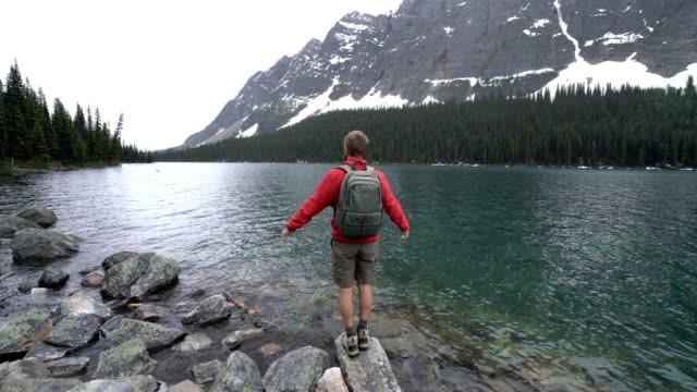 Excursionista-celebrando-por-lago-de-montaña,-4K