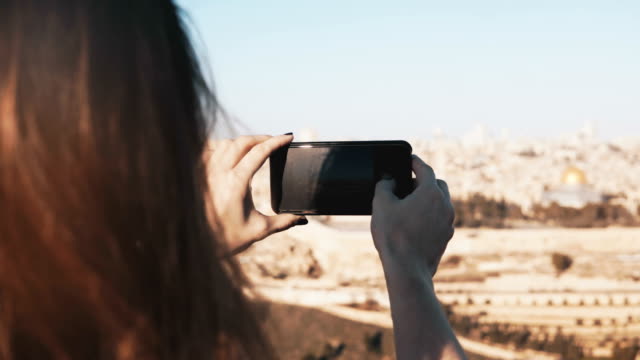 Mädchen-macht-Smartphone-Fotos-von-Jerusalem,-Israel.-Weibliche-Hände-halten-Telefon-an-einem-sonnigen-Tag.-Momente-festhalten.-4K