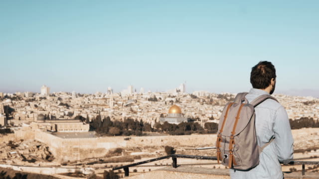 Tourist-male-takes-photos-of-Jerusalem-panorama.-Man-with-backpack-stands-at-skydeck-edge-with-smartphone.-Israel-4K