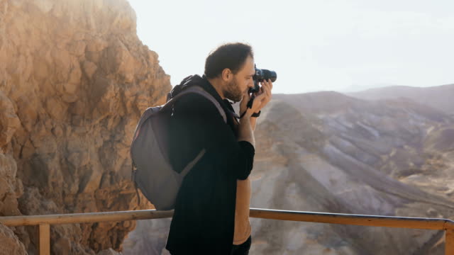 Man-takes-photos-of-massive-mountain-scenery.-Caucasian-male-with-camera-photographs-and-looks-at-his-camera.-Israel-4K