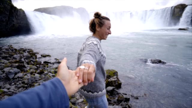 Me-siga-a-la-cascada,-novia-hacia-hombre-Godafoss-cae-en-concepto-de-viajes-de-personas-de-Islandia