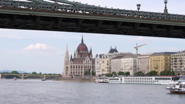 El-paisaje-del-edificio-del-Parlamento-húngaro-con-consejos-de-la-nave-en-el-Danubio-en-Budapest,-Hungría-en-la-tarde.