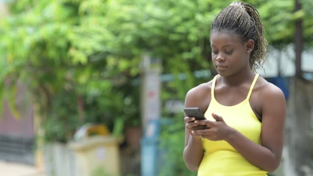 Joven-mujer-africana-feliz-con-teléfono-al-aire-libre