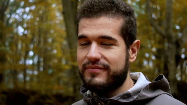 young-attractive-man-in-the-forest-jokes-and-smiles-at-the-camera