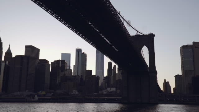 A-view-of-Lower-Manhattan-skyline-with-One-World-Trade-Center-filmed-from-the-boat-in-the-East-River-under-the-Brooklyn-Bridge-in-New-York,-United-States