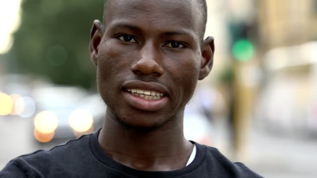Nahaufnahme-Portarit-von-afrikanischen-jungen-Mann-lächelnd-in-die-Kamera-auf-der-Straße