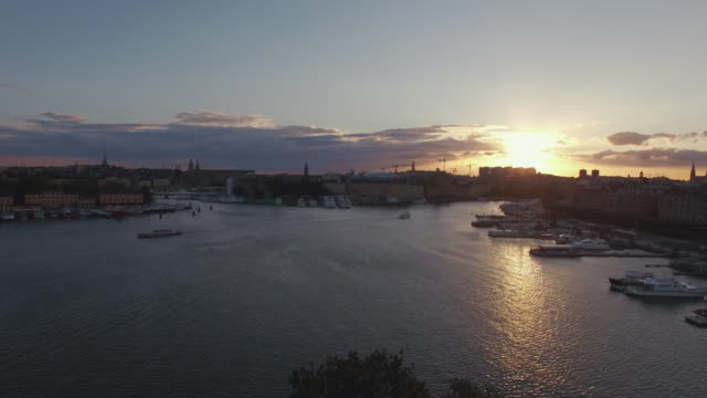 View-of-Stockholm-city-at-sunset,-ferry-boat-passing-by-on-river