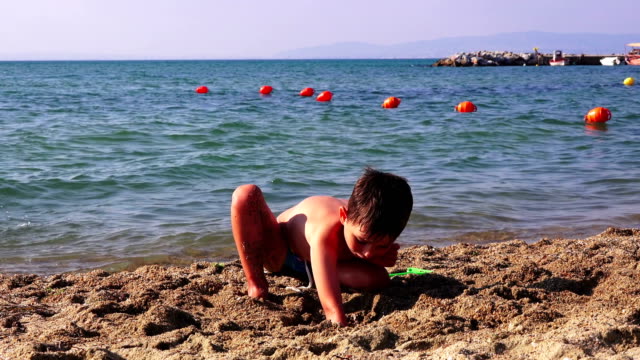 Kleiner-Junge-am-Meeresstrand-im-Sand-spielen